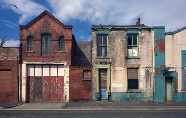 derelict houses and abandoned commercial property on a residential street with boarded up windows and decaying crumbling walls