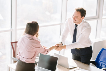 Team lead shaking manager hand in office at desk. Grateful for successful work.