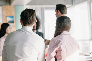 Fototapeta premium Close up image of managers backs, who attentively listening to colleagues.