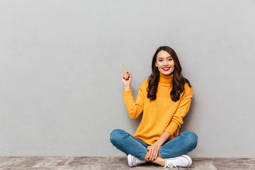 Smiling brunette woman in sweater sitting on the floor