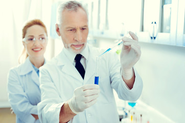 No right for mistake. Selective focus on a test tube with navy blue chemical liquid held by a lab professional conducting chemical experiment.