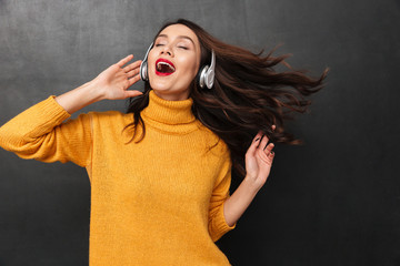 Playful brunette woman in sweater and headphone listening music