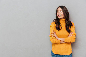 Smiling woman in sweater with crossed arms looking away