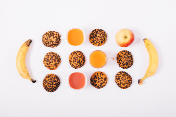 A lot of cookies, glasses of juice, bananas and apples