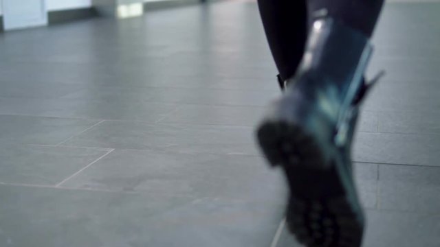 Woman walks wears black leather stylish fashionable boots, indoor slowmotion