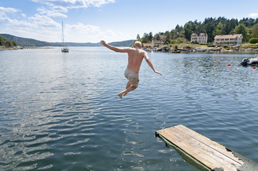 Man jumping off springboard into ocean in the summer