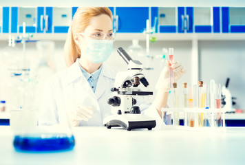 Fototapeta premium Controlled experiment. Selective focus on a microspore and a set of different test tubes standing on a table while a female researcher working in a lab.
