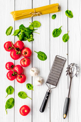 Cook spaghetti with tomatoes, garlic, basil. Italian recipe. White wooden background top view