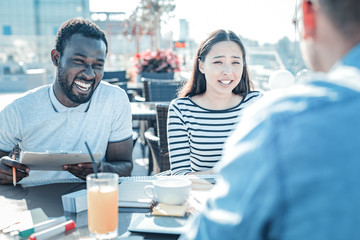 Best mates forever. Positive minded young friends having fun together and smiling cheerfully while meeting in a local cafe for a lunch.