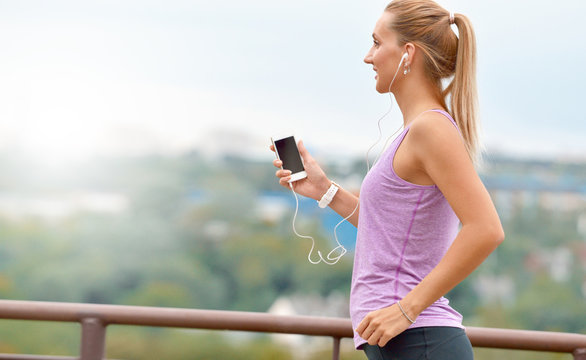 Young fitness female joger is runing and listening to music during the run