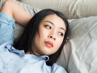 Close up of Asian woman lying in bed resting in day time.