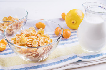 Bowl with corn flakes, jug of milk and empty bowl for prepared delicious breakfast.The concept of healthy breakfast, corn flakes with milk and fruit on wooden table, close up.