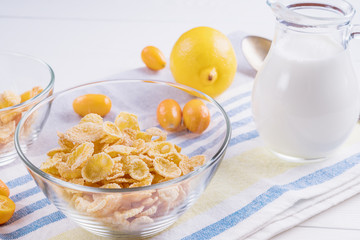 Bowl with corn flakes, jug of milk and empty bowl for prepared delicious breakfast.The concept of healthy breakfast, corn flakes with milk and fruit on wooden table, close up.