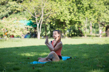 Young woman practicing yoga in the park outdoor. Concept of healthy lifestyle and relaxation.