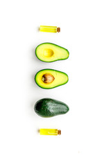 Natural products for skin care. Avocado oil in bottles near sliced avocado on white background top view copy space