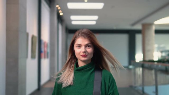 Stylish young woman wears in green walks with fashionable bag, indoor slowmotion