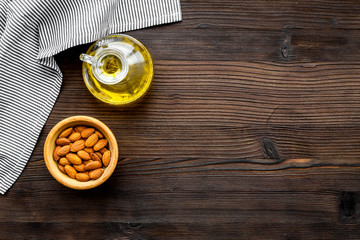 Obraz na płótnie Canvas Oil for skin care. Almond oil near almond on dark wooden background top view copy space