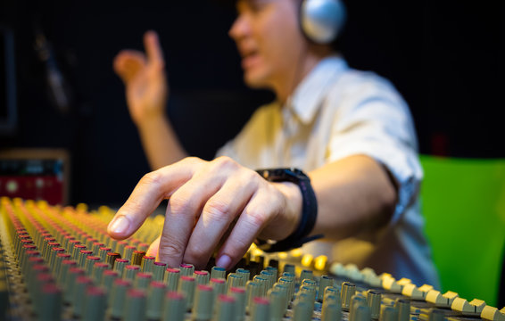 sound engineer hands working on audio mixing console in recording, broadcasting studio