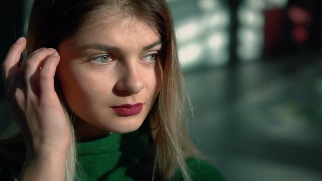 Portait of stylish young woman wears in green looking to camera, indoor slowmotion