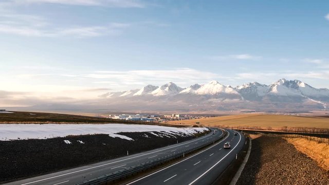 Time lapse footage of highway leading to snowy peaks of High Tatras mountains, Slovakia during a colourful sunset.