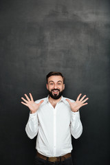 Image of male office worker gesturing on camera with hands up, being cheerful over dark gray background
