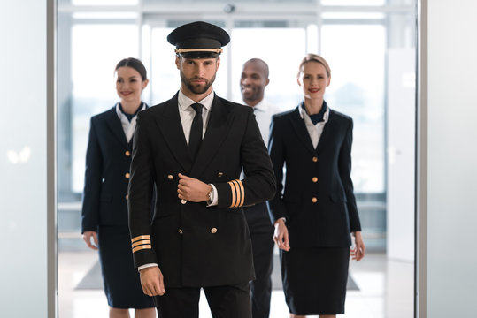 handsome pilot at airport with his team looking at camera