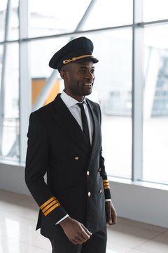 happy young pilot in professional uniform at airport