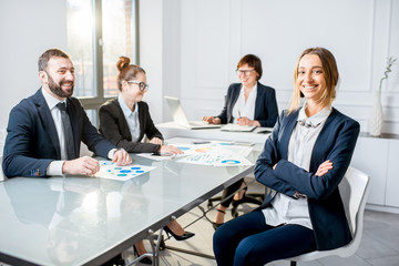 Portrait of a young businesswoman sitting during the conference with colleagues in the office