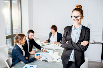 Portrait of a young businesswoman sitting during the conference with colleagues in the office