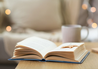 book with autumn leaf on wooden table at home