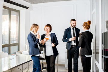 Business people talking during the meeting standing with drinks in the office