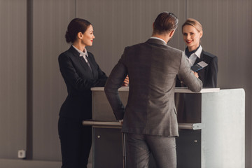 rear view of young businessman standing at airport check in counter