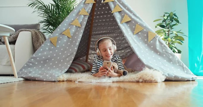 Girl using cell phone listening music in wigwam