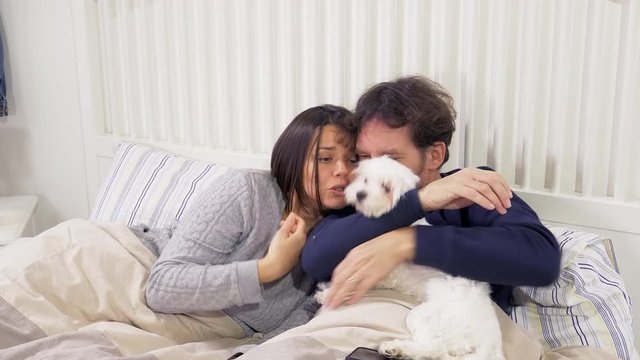 Couple in pajamas in bed talking cuddling dog