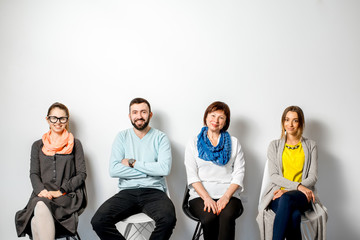 Obraz premium Portrait of a people dressed casually in colorful clothes sitting indoors on the white wall background
