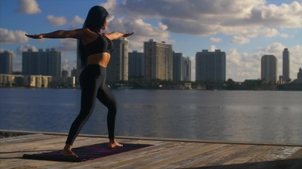 Woman stretches in cityscape at sunrise, slo-mo.