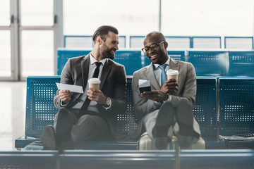 happy handsome business colleagues waiting for flight in airport lobby