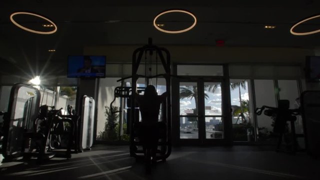 Silhouette woman works out in gym, earl morning, slo-mo.
