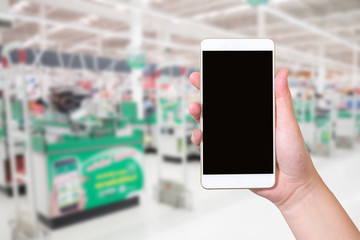 Female hand holding mobile smart phone on Supermarket blur background. network online business concept