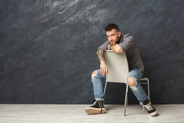 Handsome man sitting on the chair and posing in studio