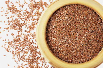 Wooden bowl with flaxseeds on white background