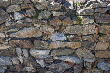 Old stone wall closeup texture, invaded by moss, weathered, a rustic wall in Spain`s countryside