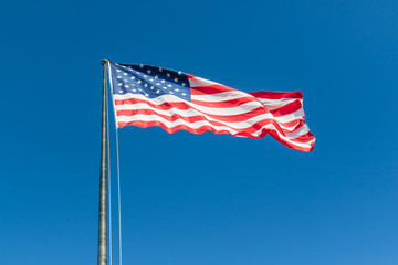 American flag flying with blue sky background