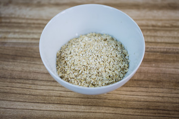 Oatmeal in a white cup, wooden background