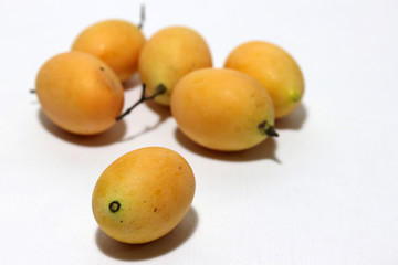 Bouea macrophylla, commonly known as gandaria put stack on white background. The orange color of fruit in tropical zone.