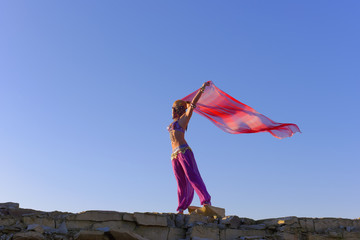 A beautiful blonde oriental belly dancer dressed in a purple  colored belly dance costume relaxes...