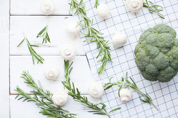 Diet, Healthy Food Cooking, Vegetarian Concept. Button mushrooms, broccoli and rosemary mock up on a white wooden table and plaid napkin, top view