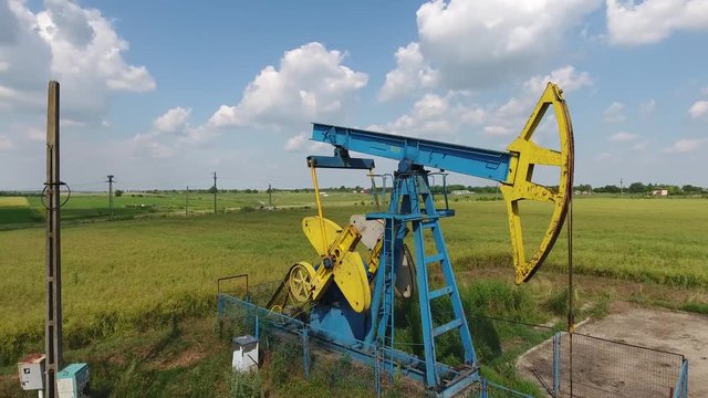 4K Aerial Shot Of A Pump Jack In The Middle Of A Green Field