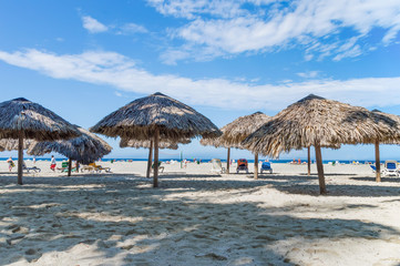 parasols on the shores of the Atlantic Ocean, on the background of sand, sky and people on the horizon, Varadero, Cuba