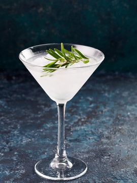 Glass of Martini coctail with fresh rosemary and lime on blue background.
